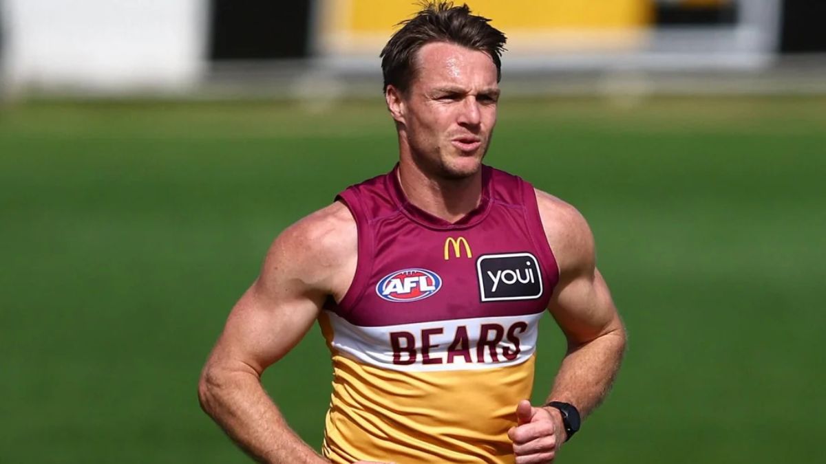 AFL player in maroon-and-gold Bears jersey sprinting on a green training field, sponsor logos visible on chest.
