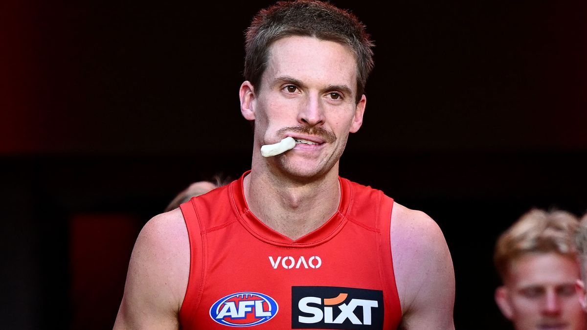 Male athlete in a red sleeveless AFL jersey chewing a white mouthguard.
