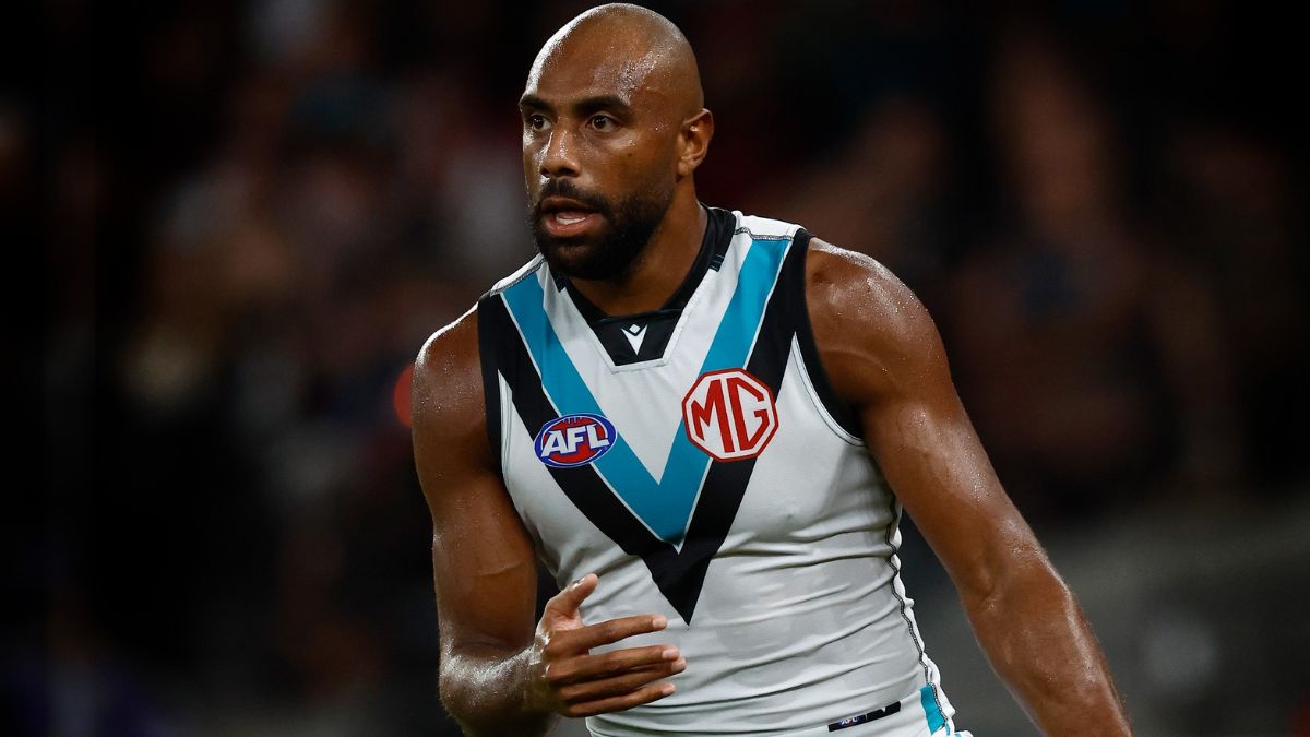 Athlete in a white AFL jersey with blue chevron and MG badge, running on the field during a game.