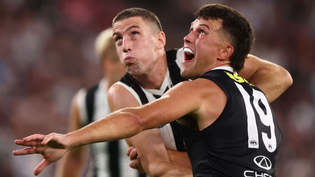 Two AFL players grapple for the ball during a dense contest, one in a black jersey with number 19, the other behind.